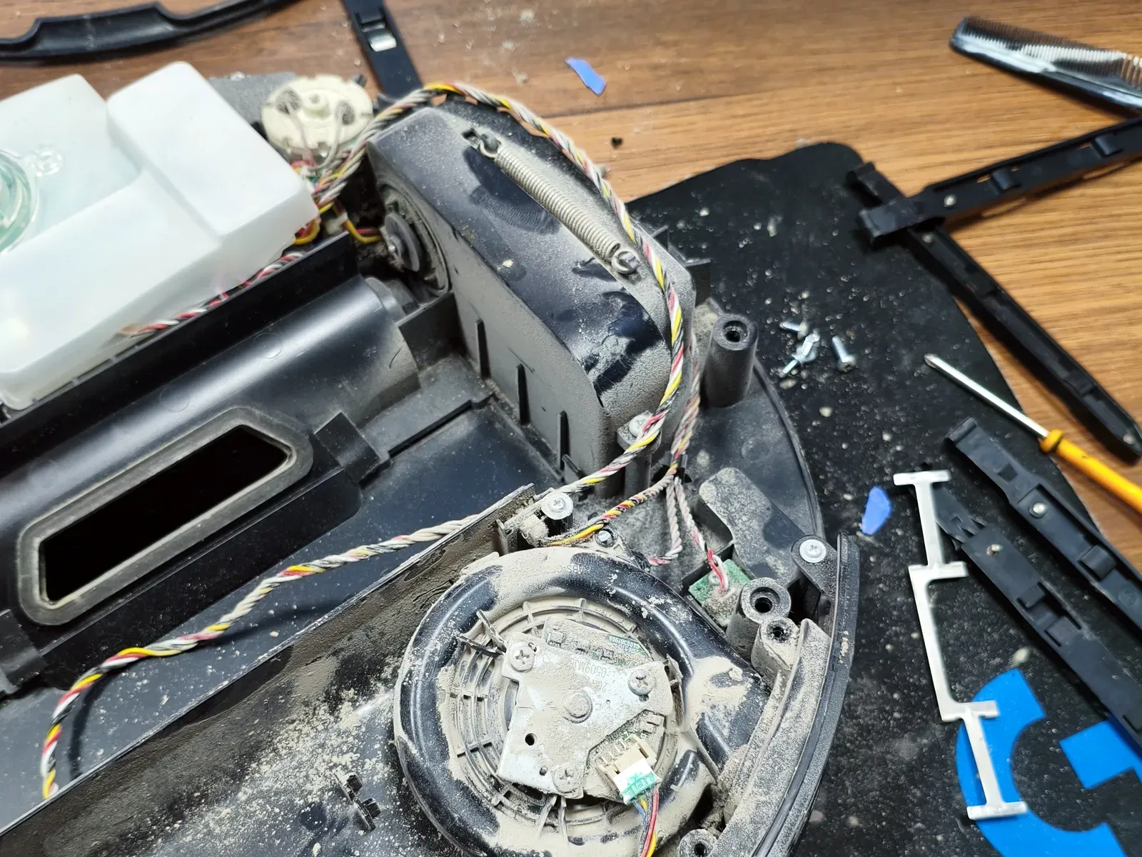 Robot süpürgenin sökülmüş alt gövdesi, fan yatağı ve çevresi kalın toz tabakasıyla kaplı