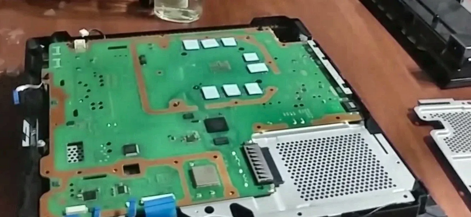 PS4 anakartının metal kalkanlı yüzü, söküm sırasında tezgâhta